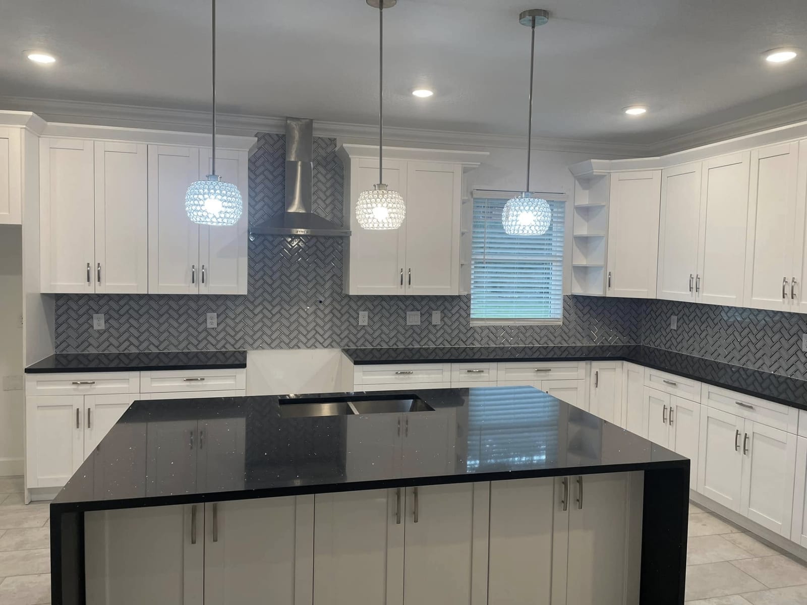 Black granite kitchen island with white cabinetry and pendant lighting